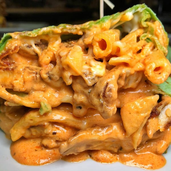 A close-up of a Pantano's Eatery sandwich, filled with pasta and a creamy orange sauce.