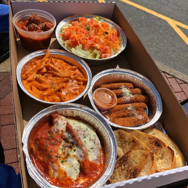 Pantano's Eatery takeout box with meatballs, salad, penne, mozzarella sticks, chicken parmesan, and garlic bread.